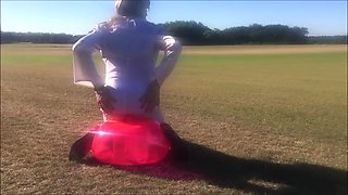Crossdresser slut rides dildo outdoors in a field