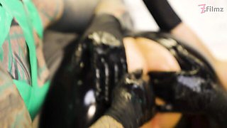 Latex mistress Miss Flora fists her slave while his cock stays locked in a cage