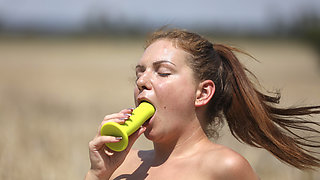 Fit village girl plays with green toy naked in sunny open field